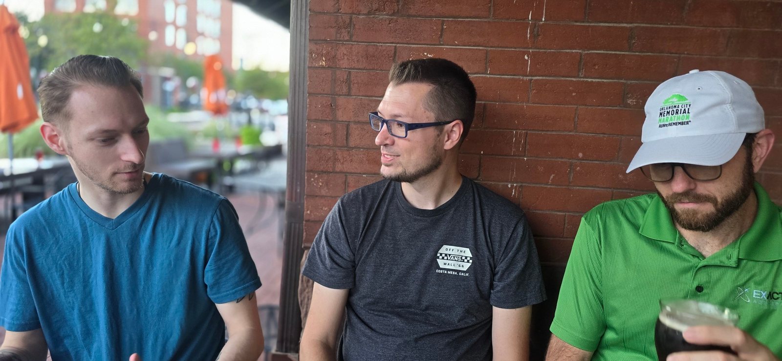 Three people mid-conversation on the patio at a Beer & Spirituality night