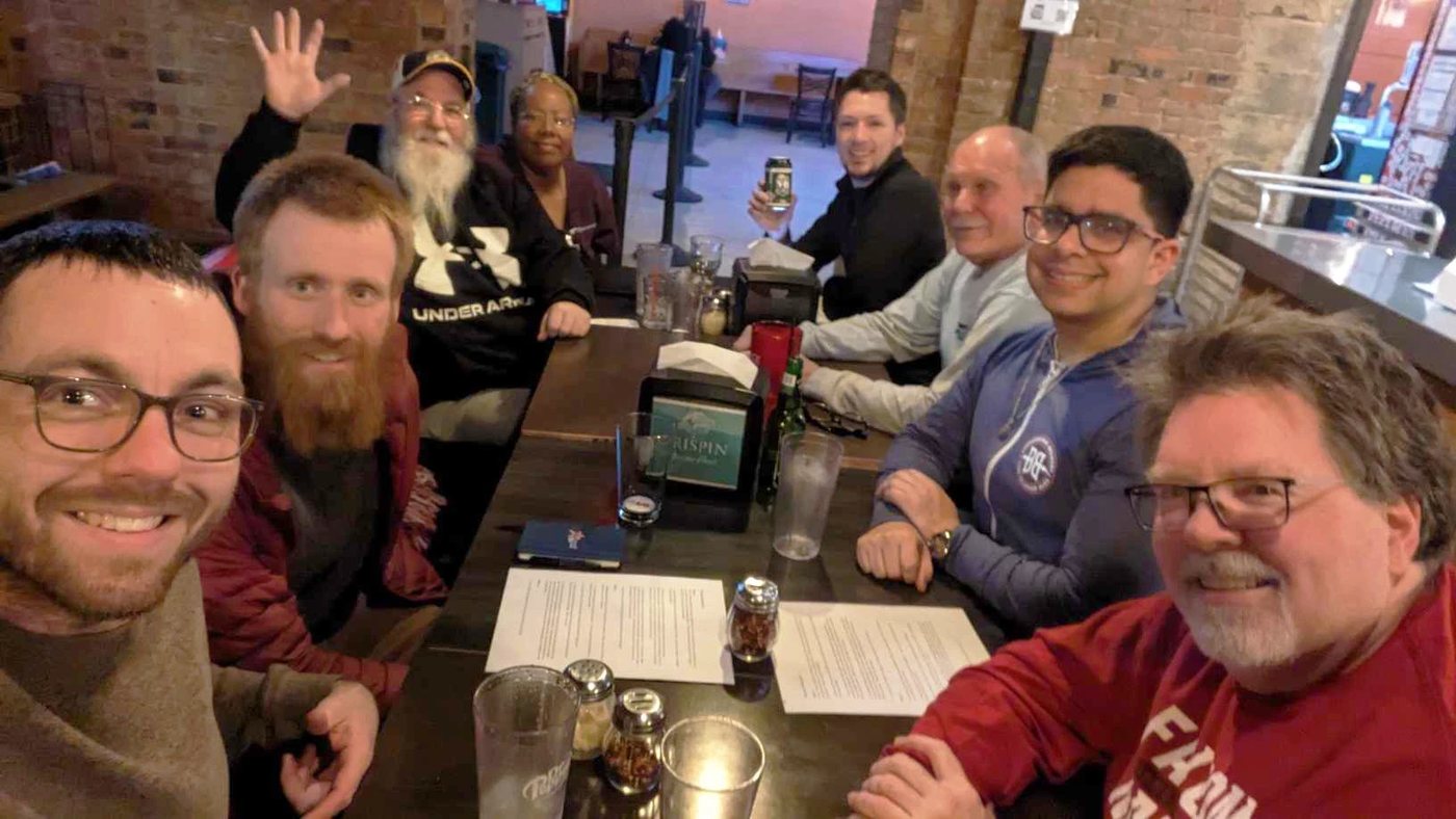 A full table at Beer & Spirituality, everyone turned toward the camera